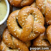 Pillowy Soft Gluten-Free Pretzels Simple Recipe 17 Close up overhead view of a gluten-free pretzel that shows the golden brown color of the pretzel and the white salt flakes with a bowl of mustard dipping sauce off to the left side
