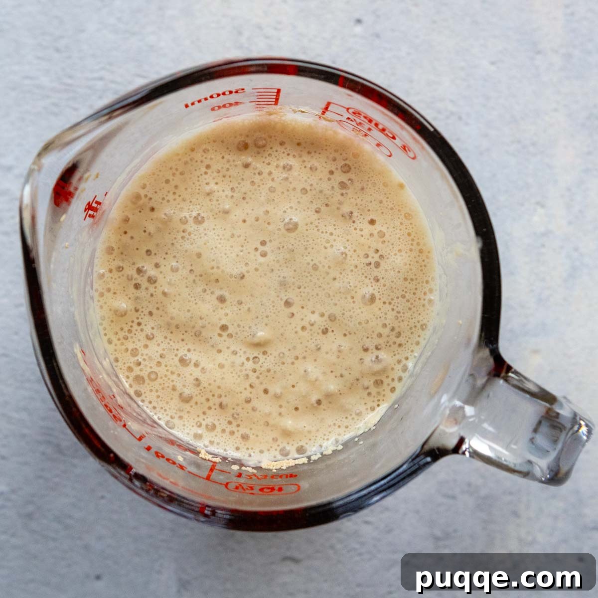Pillowy Soft Gluten-Free Pretzels Simple Recipe 3 Yeast and warm water ingredients in a glass measuring cup, showing frothy activated yeast.