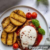 Overhead shot of chicken parmesan with grilled polenta rounds next to it on a white plate, highlighting the complete meal.
