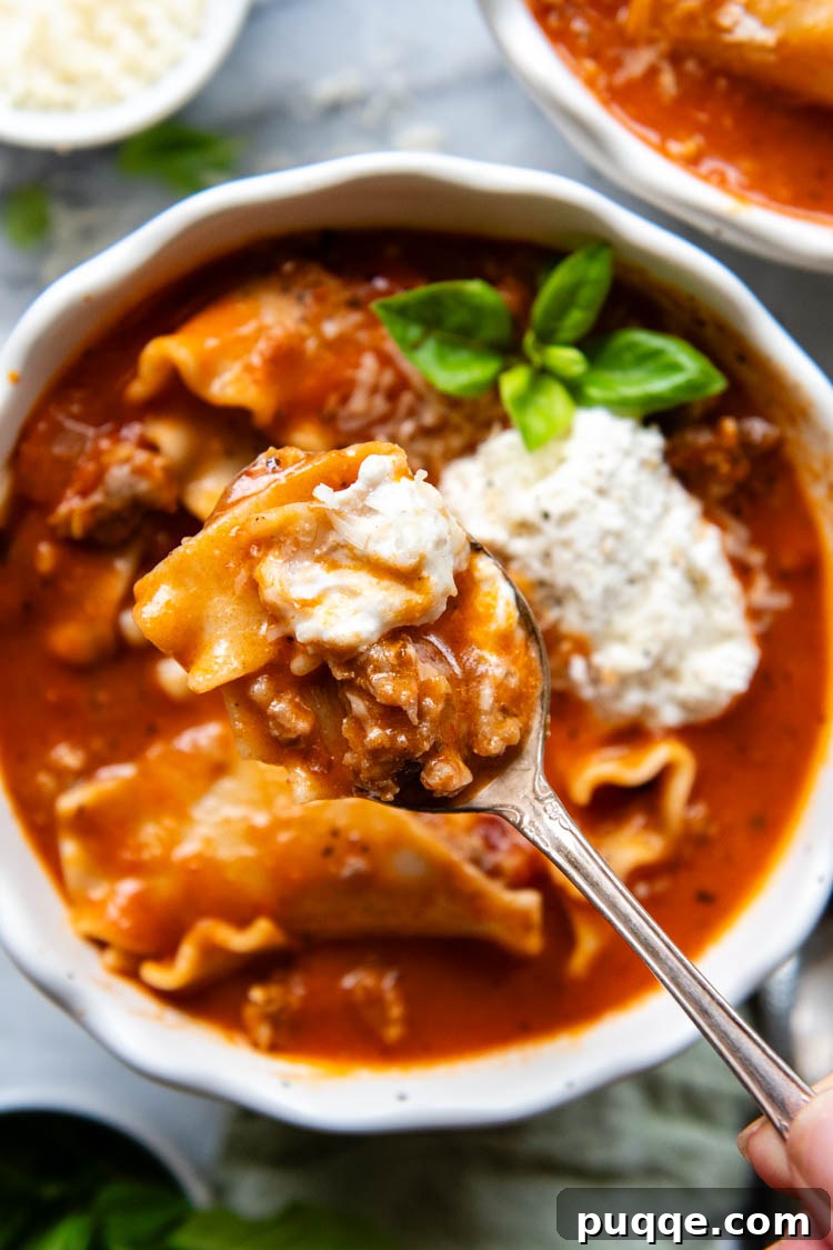 Ultimate 30-Minute Gluten-Free Lasagna Soup 7 A close-up of a white bowl filled with steamy lasagna soup, generously topped with a creamy ricotta mixture and garnished with fresh green basil leaves. A truly inviting meal.