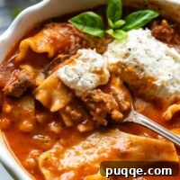 Gluten-Free Lasagna Soup displayed in a white bowl with a garnish of greenery and a spoon.