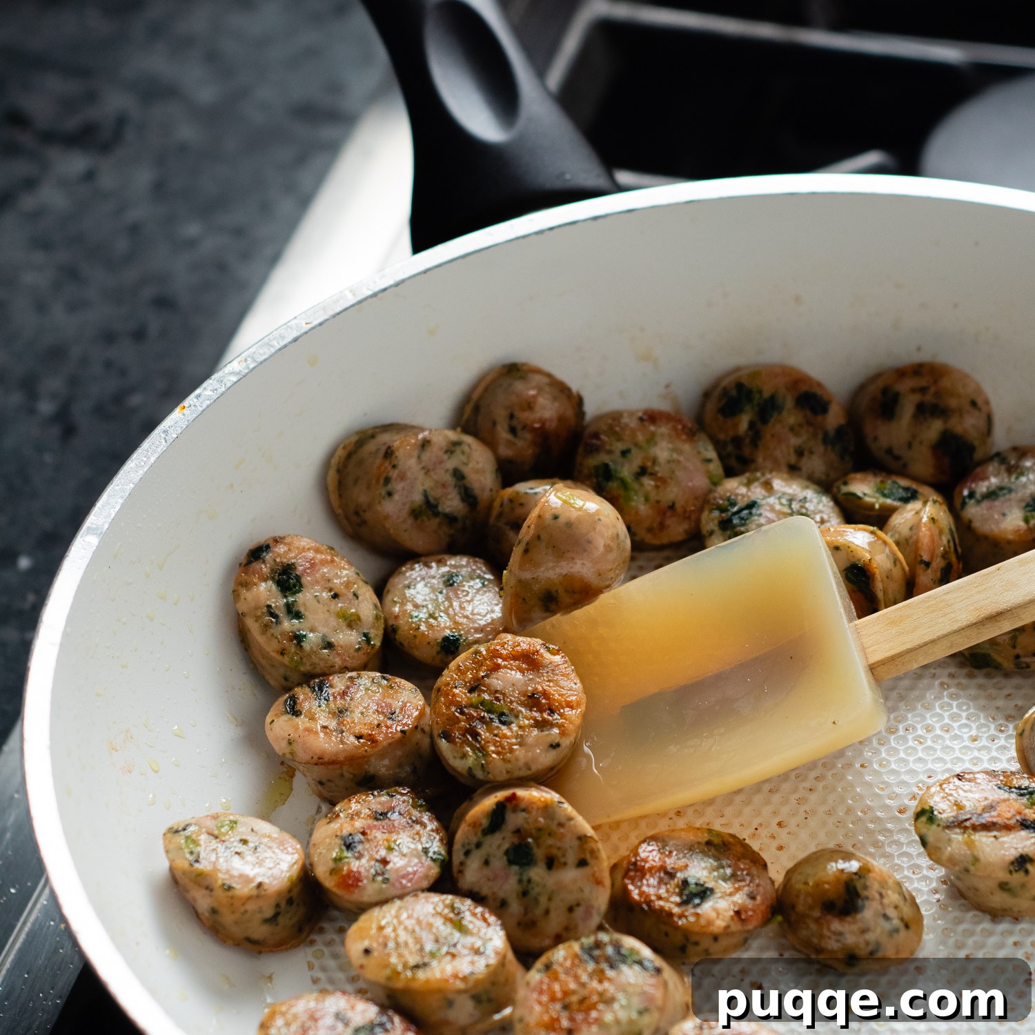 Chicken sausage medallions sizzling and browning in a pan with olive oil.