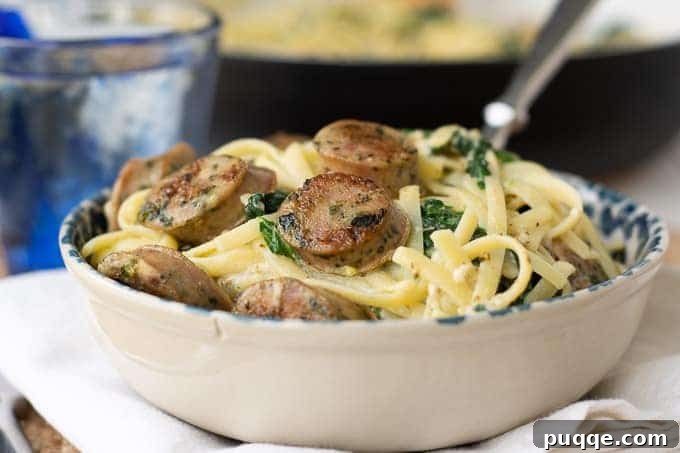 A bowl of creamy sausage pasta with a fork ready to take a bite, highlighting the texture and richness.
