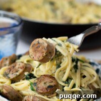 A fork lifting up a bite of creamy sausage pasta