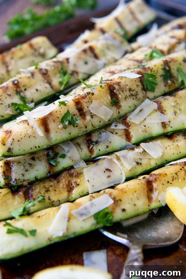 Summer's Best Grilled Zucchini and Squash 4 a grilled zucchini spear with lemon wedges around it.