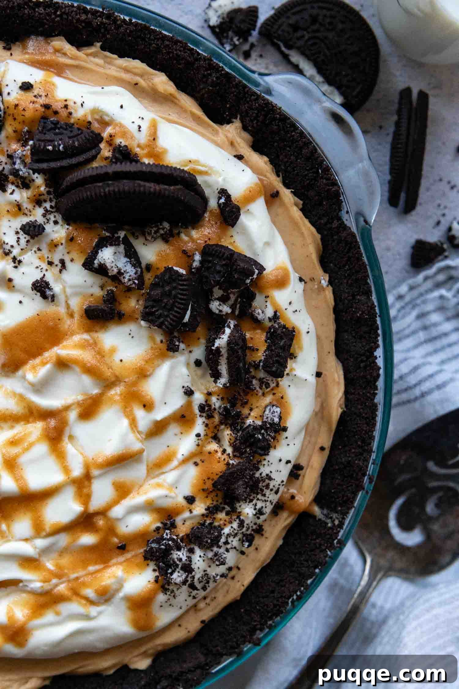 A completed peanut butter Oreo pie in a glass pie plate, beautifully drizzled with caramel topping and garnished with extra Oreos, ready to be served.