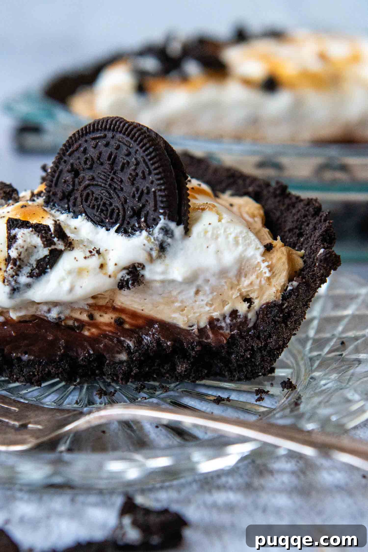 A perfectly portioned slice of peanut butter Oreo pie on a small glass plate, adorned with an Oreo cookie, highlighting the creamy layers and crunchy crust.