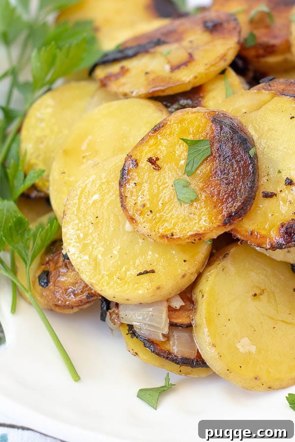 A close-up of golden-brown grilled potatoes on a white plate, garnished with fresh parsley.