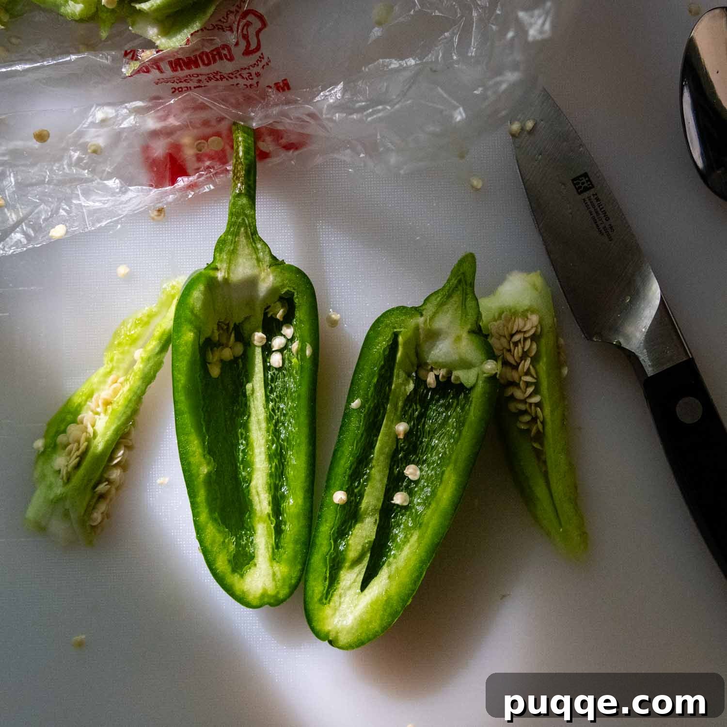 Crispy Baked Gluten-Free Jalapeño Poppers (Grain-Free) 3 A fresh jalapeño with seeds and membrane on a cutting board next to a knife, illustrating the initial cut.
