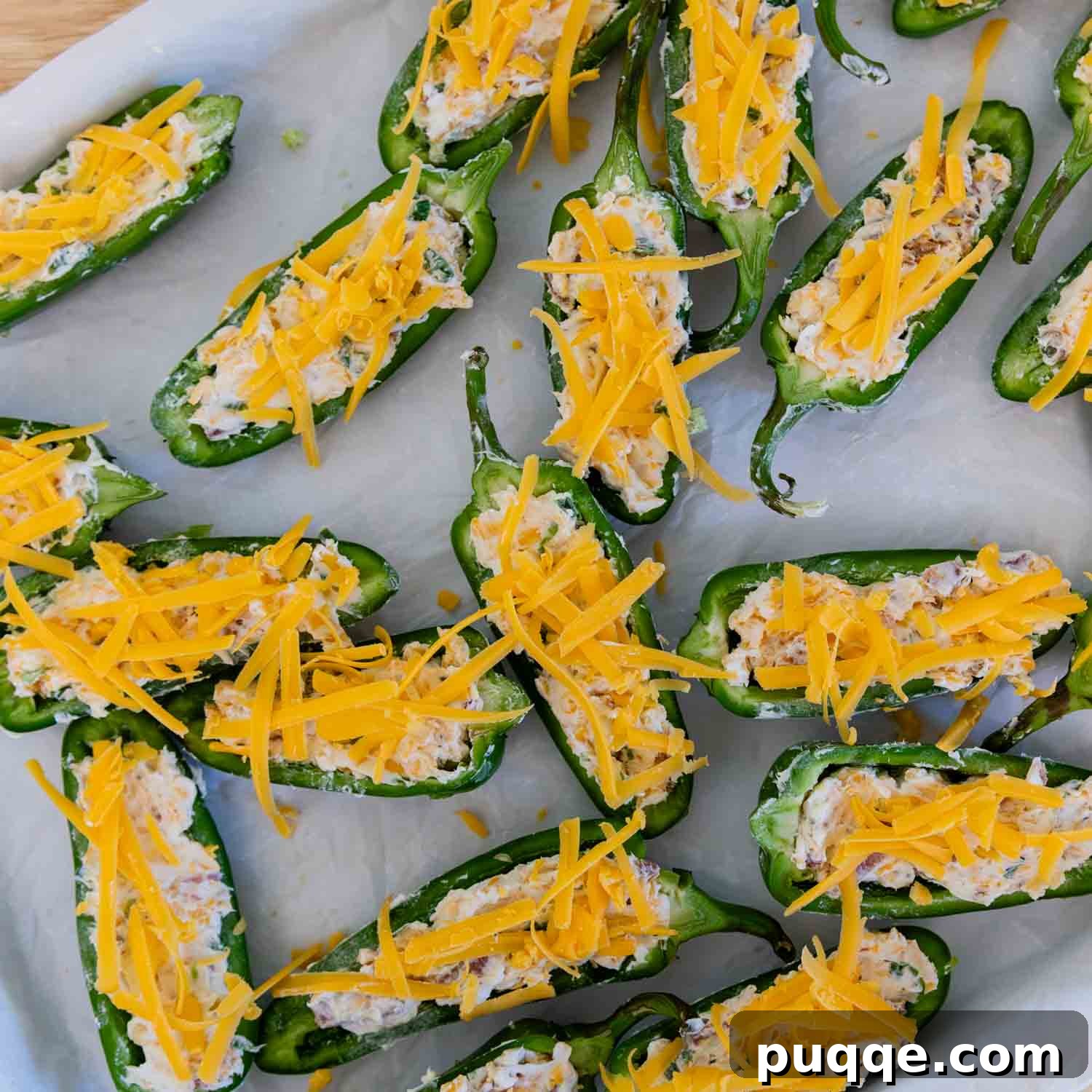 Crispy Baked Gluten-Free Jalapeño Poppers (Grain-Free) 7 Jalapeño halves filled and topped with extra cheddar cheese and bacon, ready to be baked on a baking sheet.