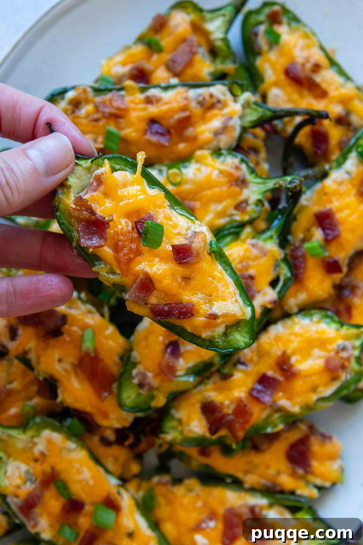 Crispy Baked Gluten-Free Jalapeño Poppers (Grain-Free) 8 A hand holding a single perfectly baked jalapeño popper, showing its golden-brown topping and creamy filling.