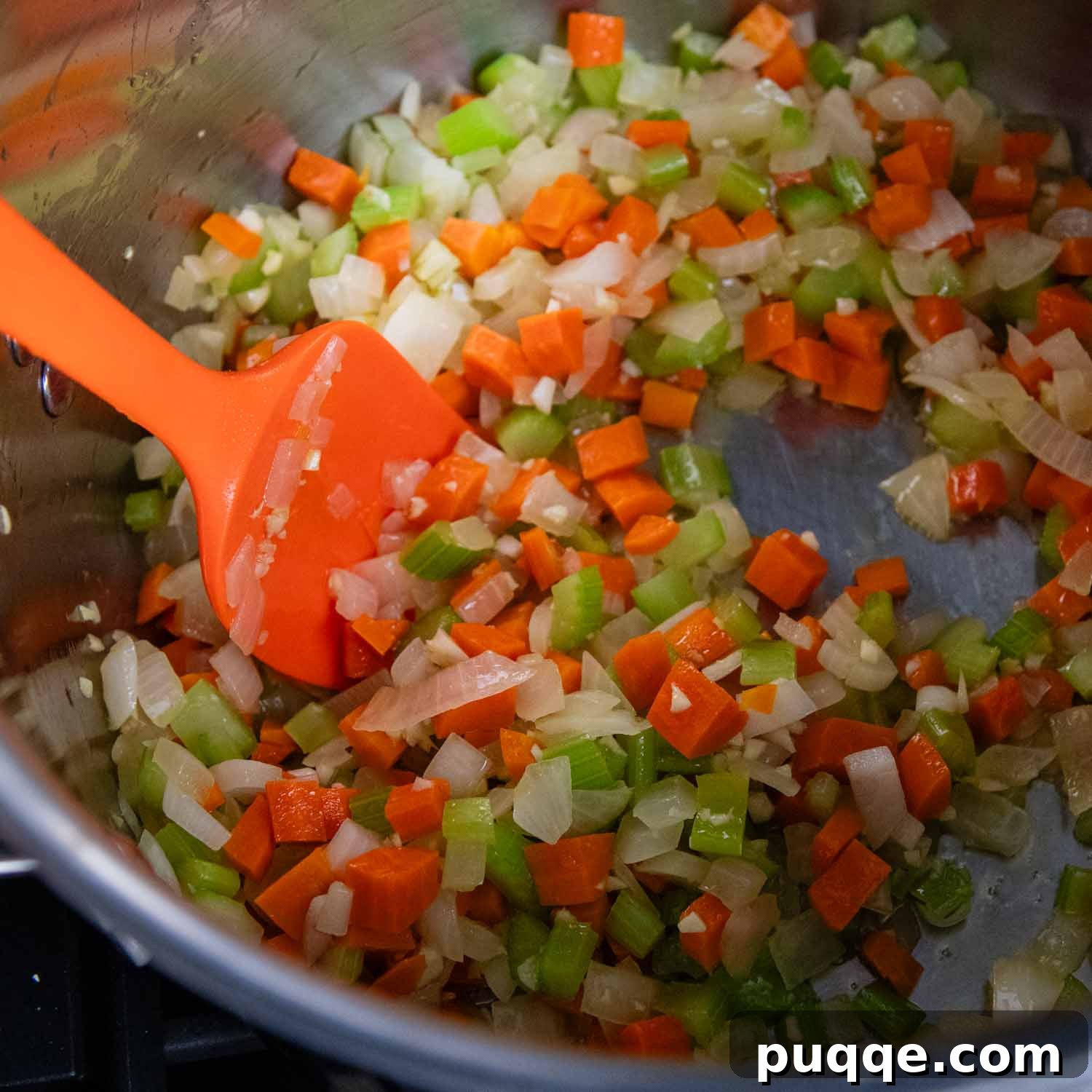 Diced onions, carrots, and celery sautéing in olive oil in a large Dutch oven, creating an aromatic base for the soup.