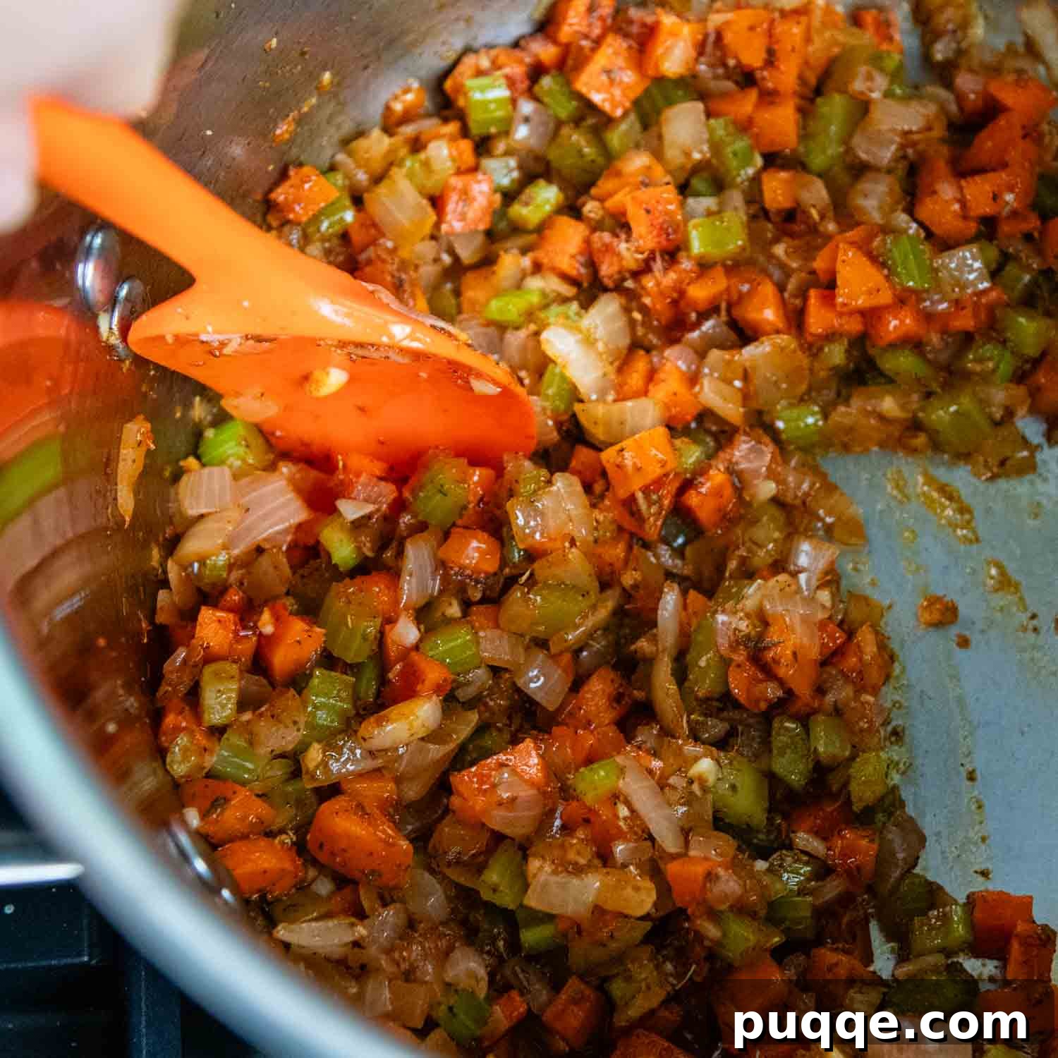 Tomato paste, minced garlic, and aromatic spices being stirred into sautéed vegetables in a pot.