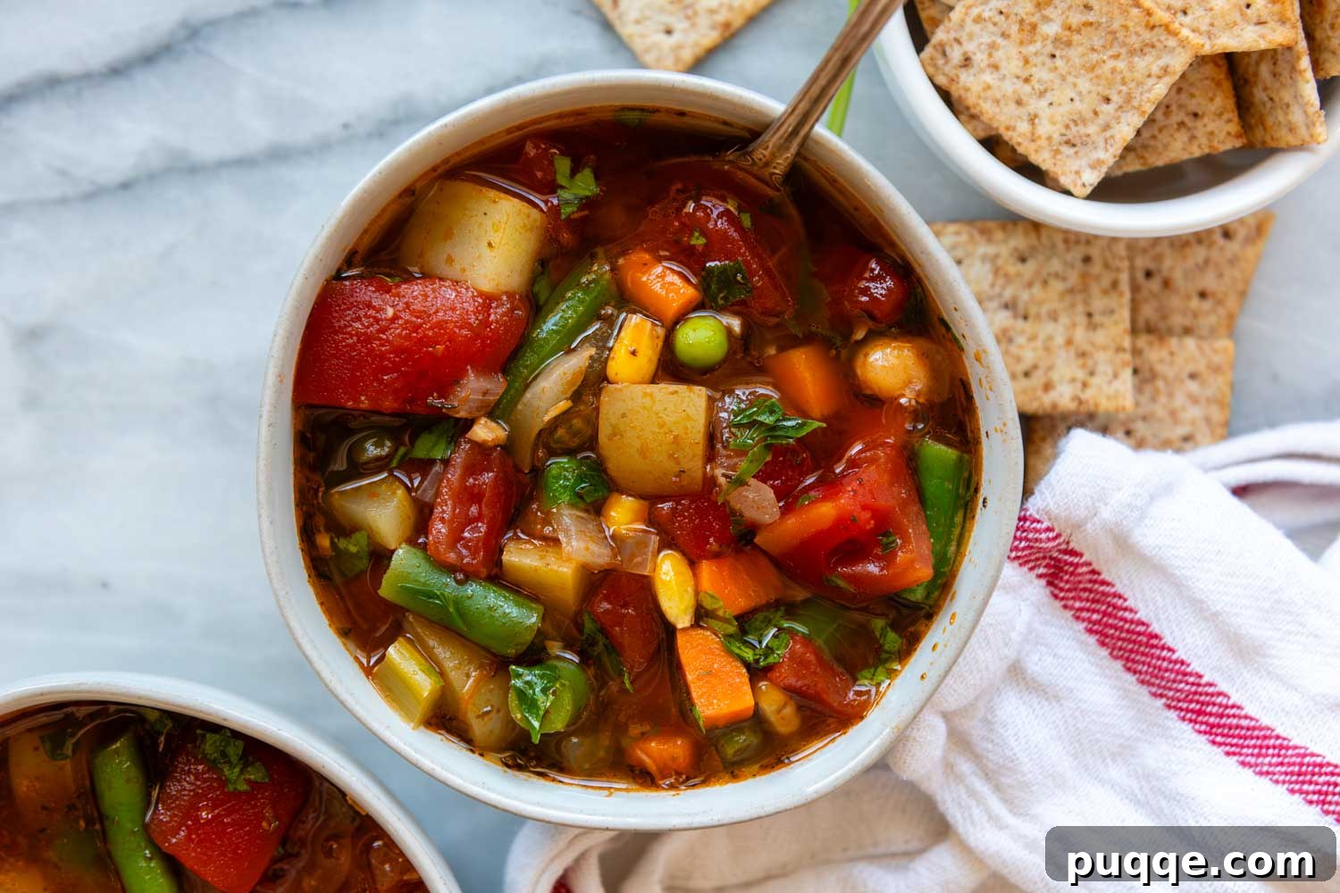 A rustic scene of a bowl of homemade vegetable soup surrounded by savory crackers, ready for a cozy meal.