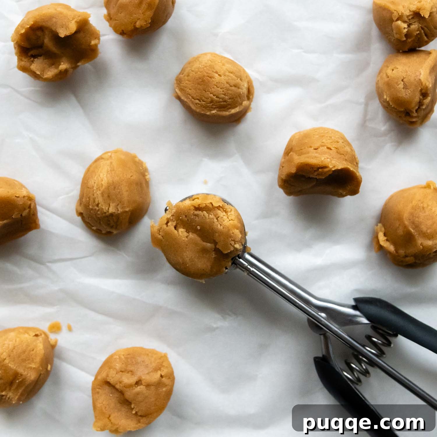 Old-Fashioned Tender Gluten-Free Peanut Butter Blossoms 4 A scoop with round cookie balls on parchment.
