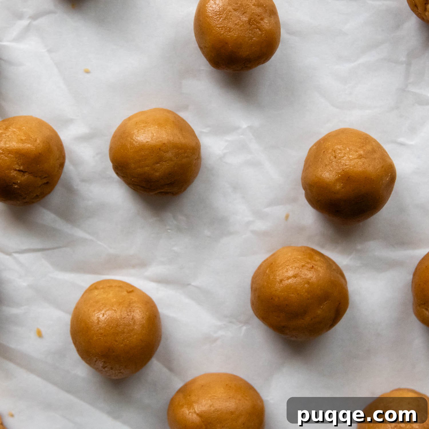 Old-Fashioned Tender Gluten-Free Peanut Butter Blossoms 5 Cookie balls on parchment paper.