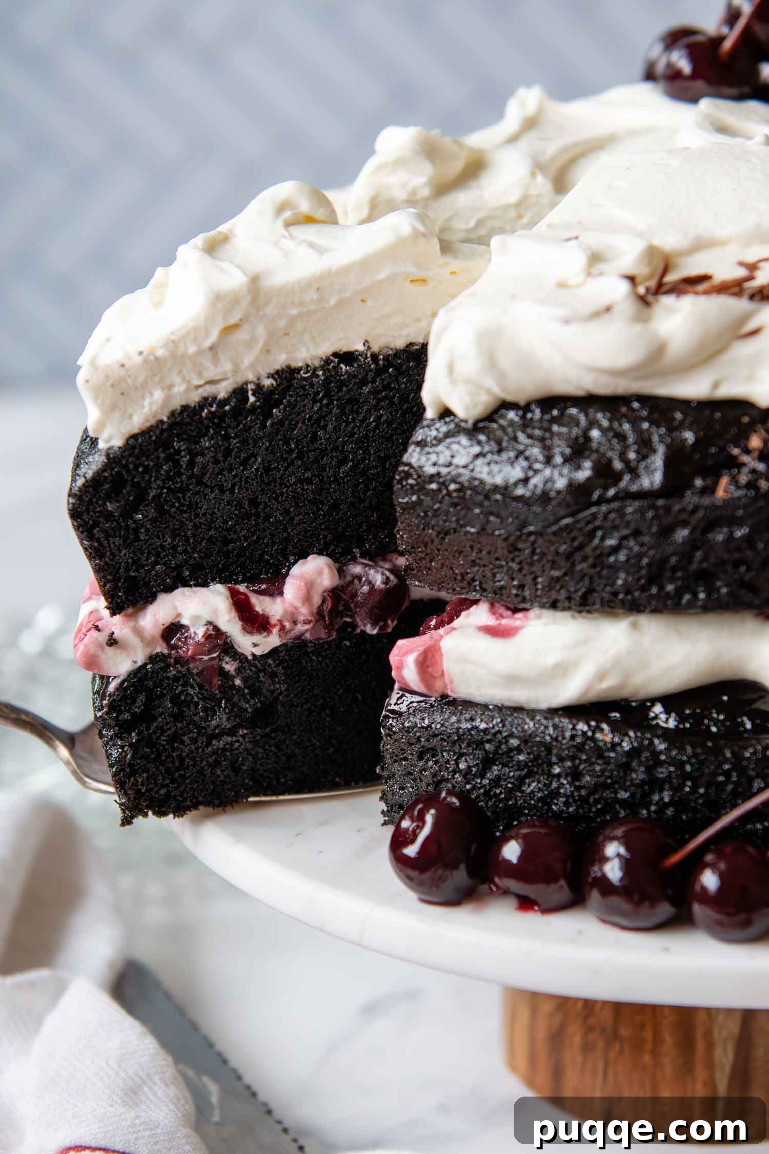 Close up of a beautifully decorated Gluten-Free Black Forest Cake slice, showcasing its layers of moist chocolate cake, whipped cream, and cherries.