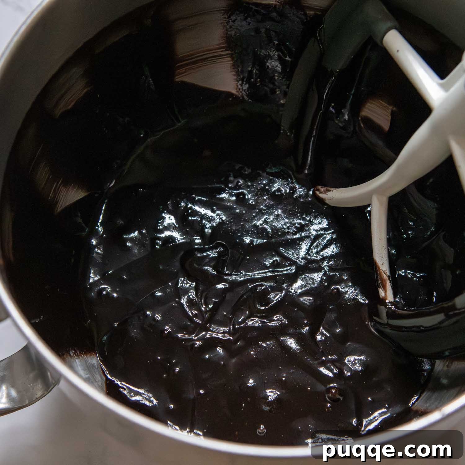 Rich chocolate cake batter being mixed in a bowl, showing a smooth, pourable consistency.