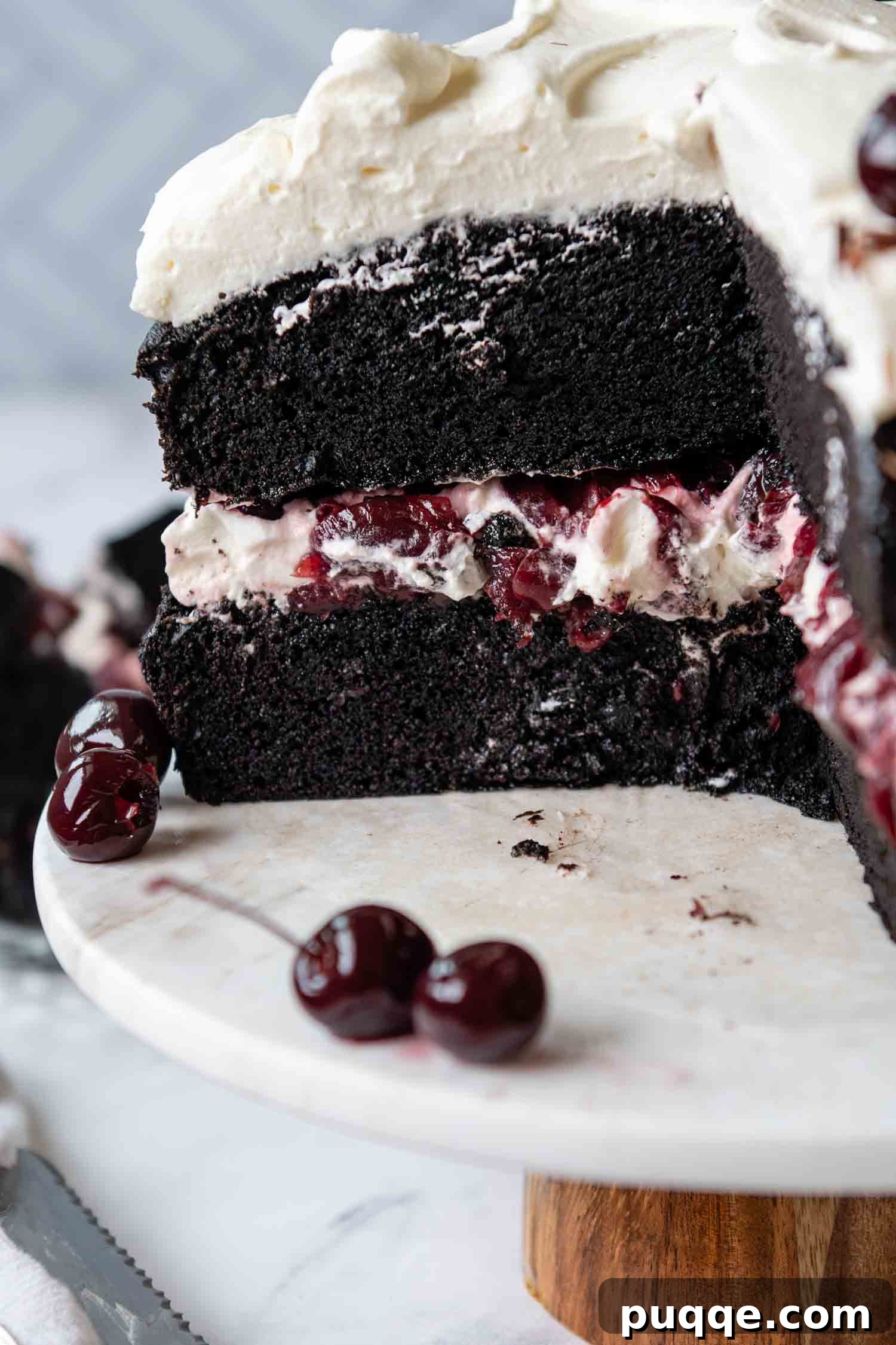 A large slice of the completed Gluten-Free Black Forest Cake has been removed, revealing the exquisite interior layers of chocolate cake, cherries, and whipped cream.