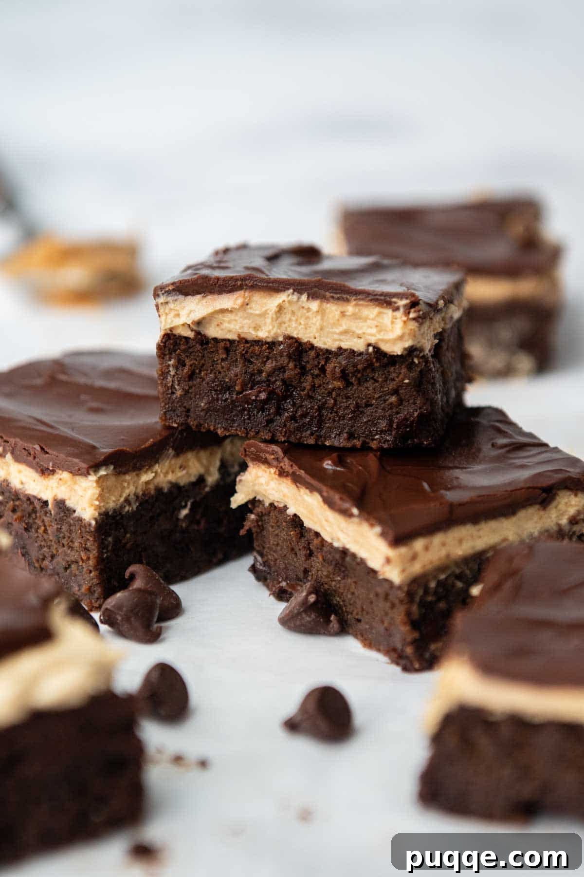 Effortless Gluten Free Zucchini Brownies 2 One perfectly frosted gluten-free zucchini brownie with peanut butter frosting and chocolate glaze, surrounded by two other brownies and chocolate chips.