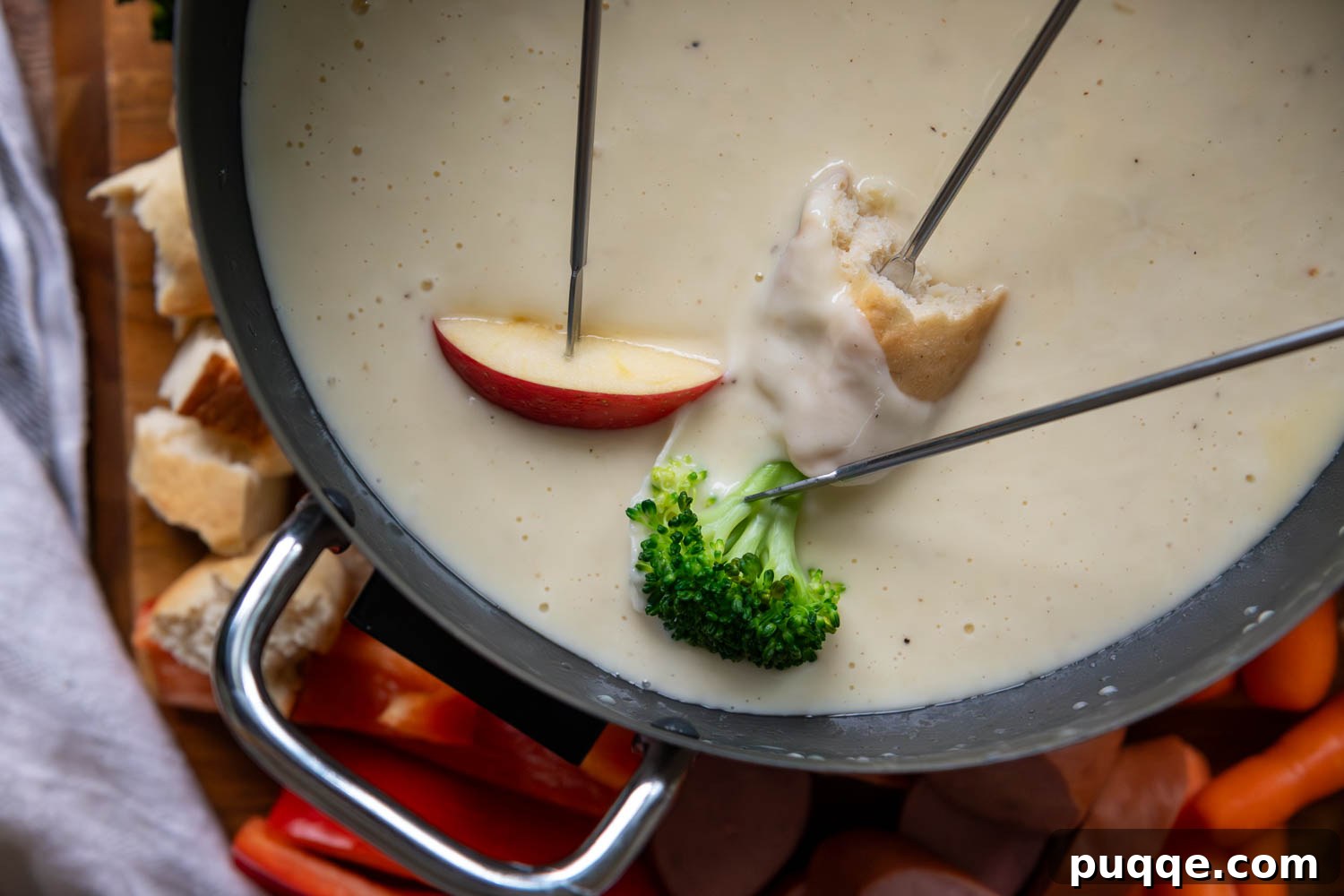 Effortless Creamy Gluten-Free Cheese Fondue 8 A vibrant assortment of gluten-free dippers including crisp apple slices, fresh broccoli florets, and a piece of golden bread, all poised around a bubbling pot of cheese fondue, inviting a communal dipping experience.