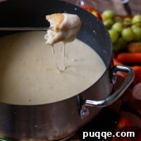 Effortless Creamy Gluten-Free Cheese Fondue 9 A delectable piece of bread, generously coated in creamy cheese, captured just after being dipped in a rich, warm pot of Gluten-Free Cheese Fondue, ready to be savored.
