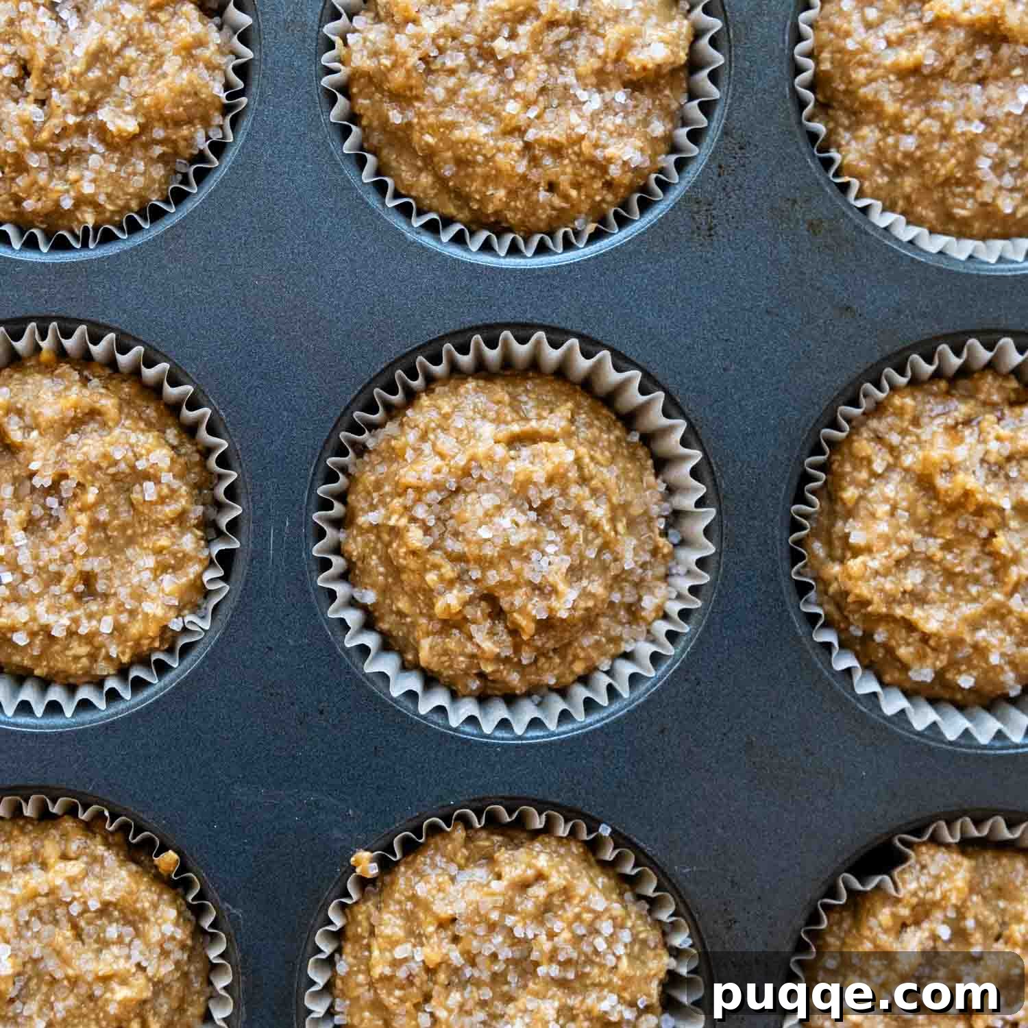 Uncooked muffin mix scooped into a muffin tin, ready for baking.