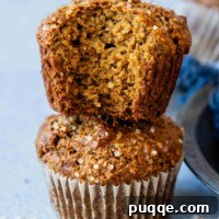 Two Gluten-Free Bran Muffins stacked with the top muffin having a bit taken out of it showing the inside texture.