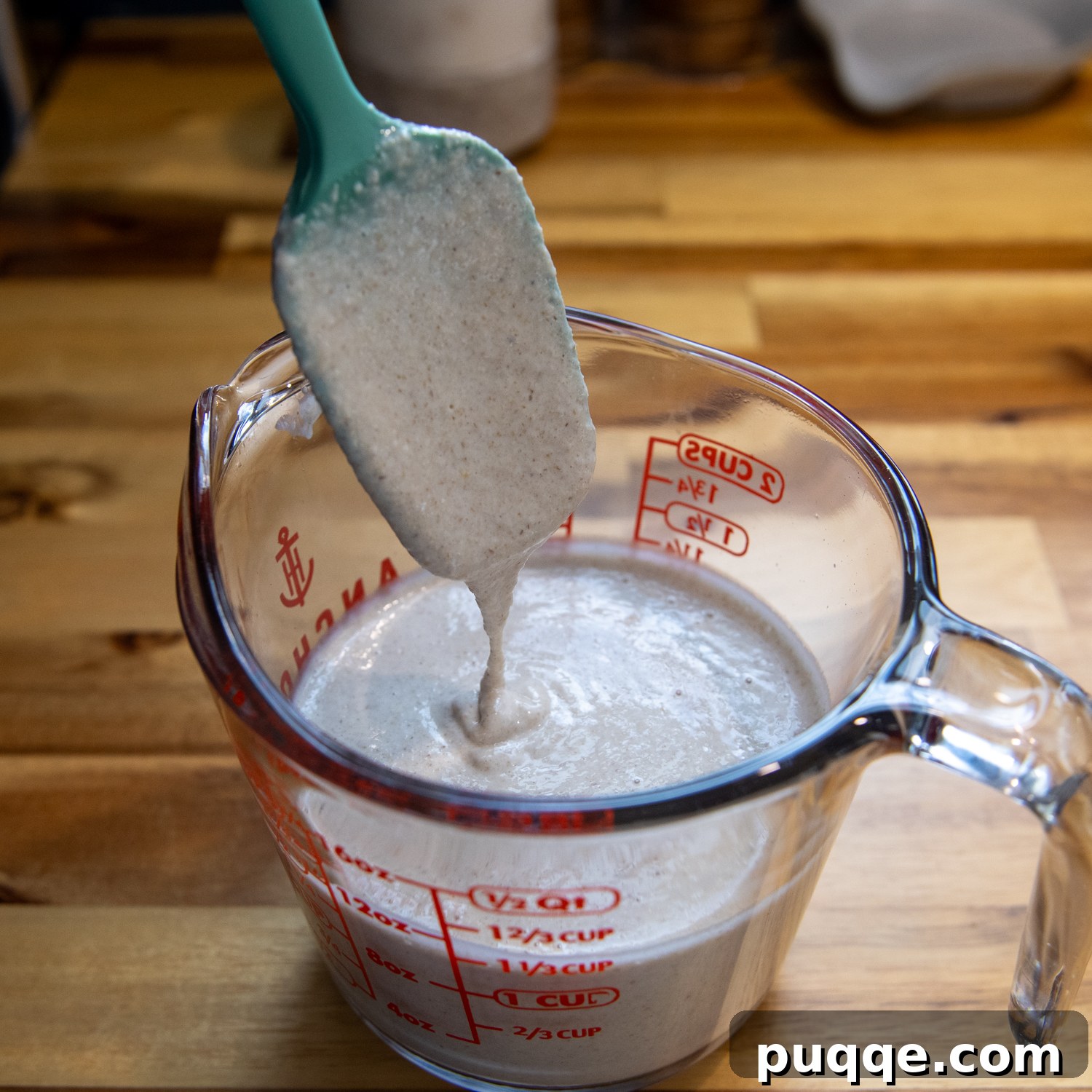 Effortlessly Soft and Pliable Oat Tortillas 5 Mixed tortilla batter in a glass measuring cup, with a silicone spatula demonstrating its evolving consistency.