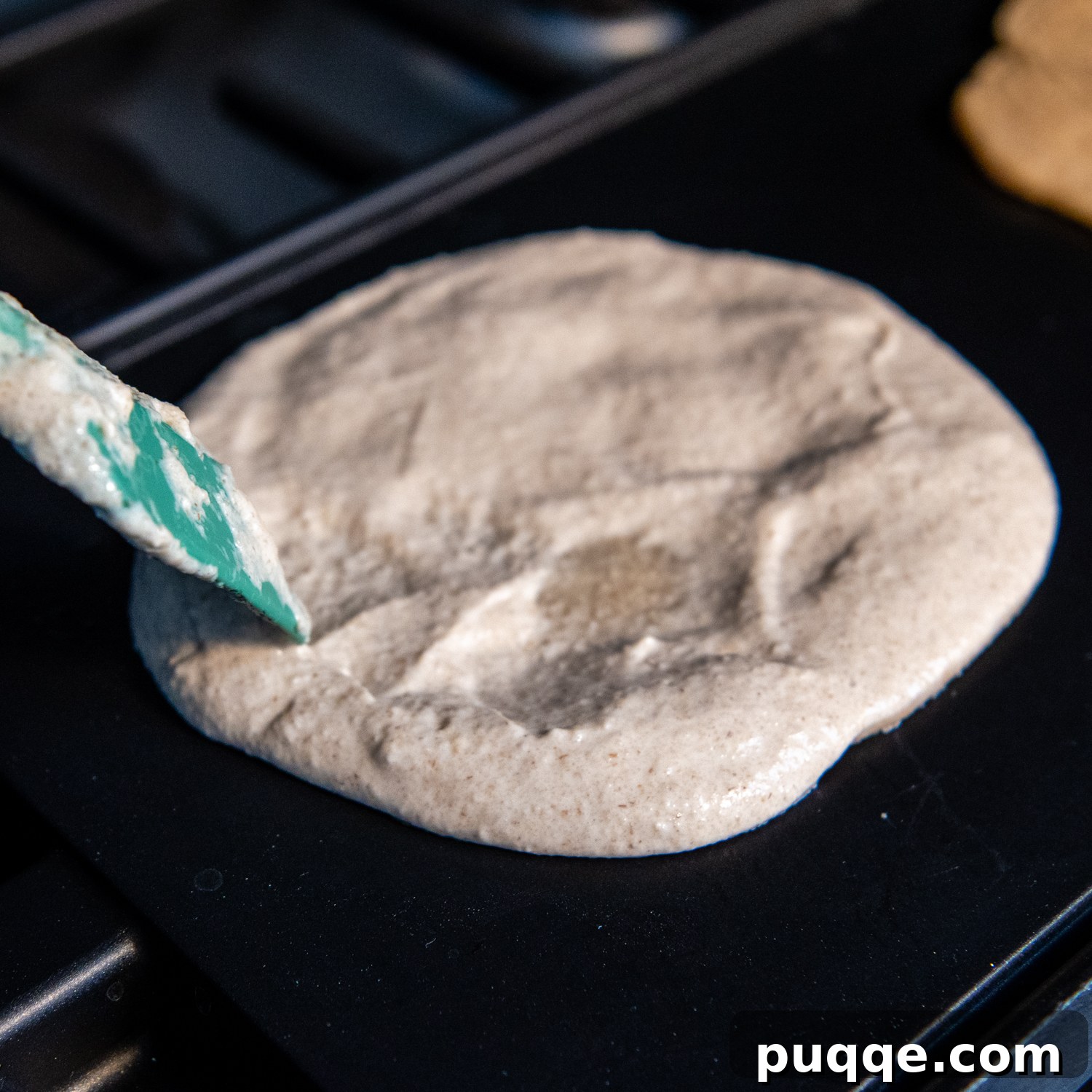 Effortlessly Soft and Pliable Oat Tortillas 6 Spatula actively spreading thin tortilla mix on a hot griddle to form a perfect circle.