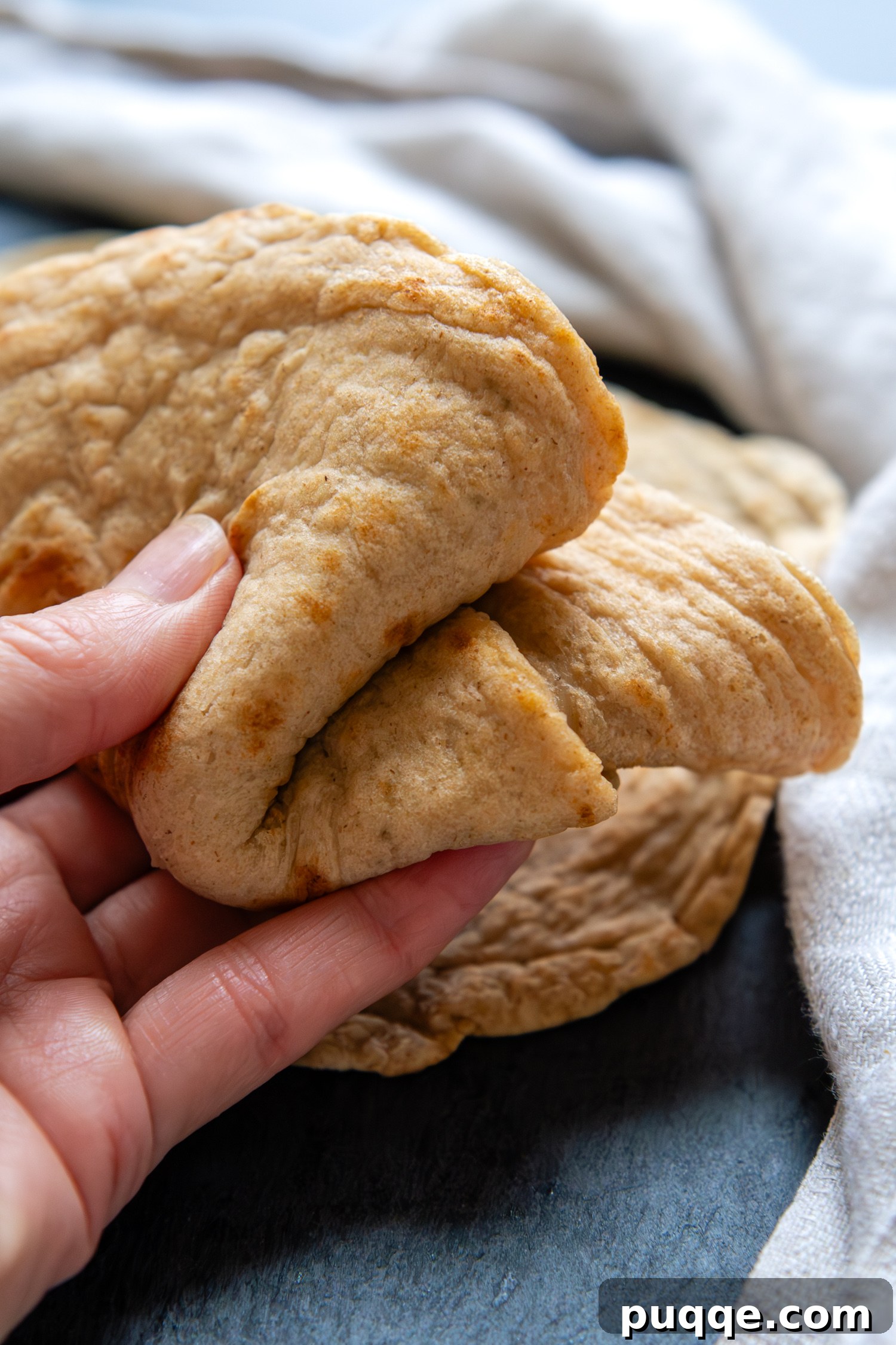 Effortlessly Soft and Pliable Oat Tortillas 10 A hand gracefully holding a folded oat tortilla, emphasizing its flexible and inviting texture.
