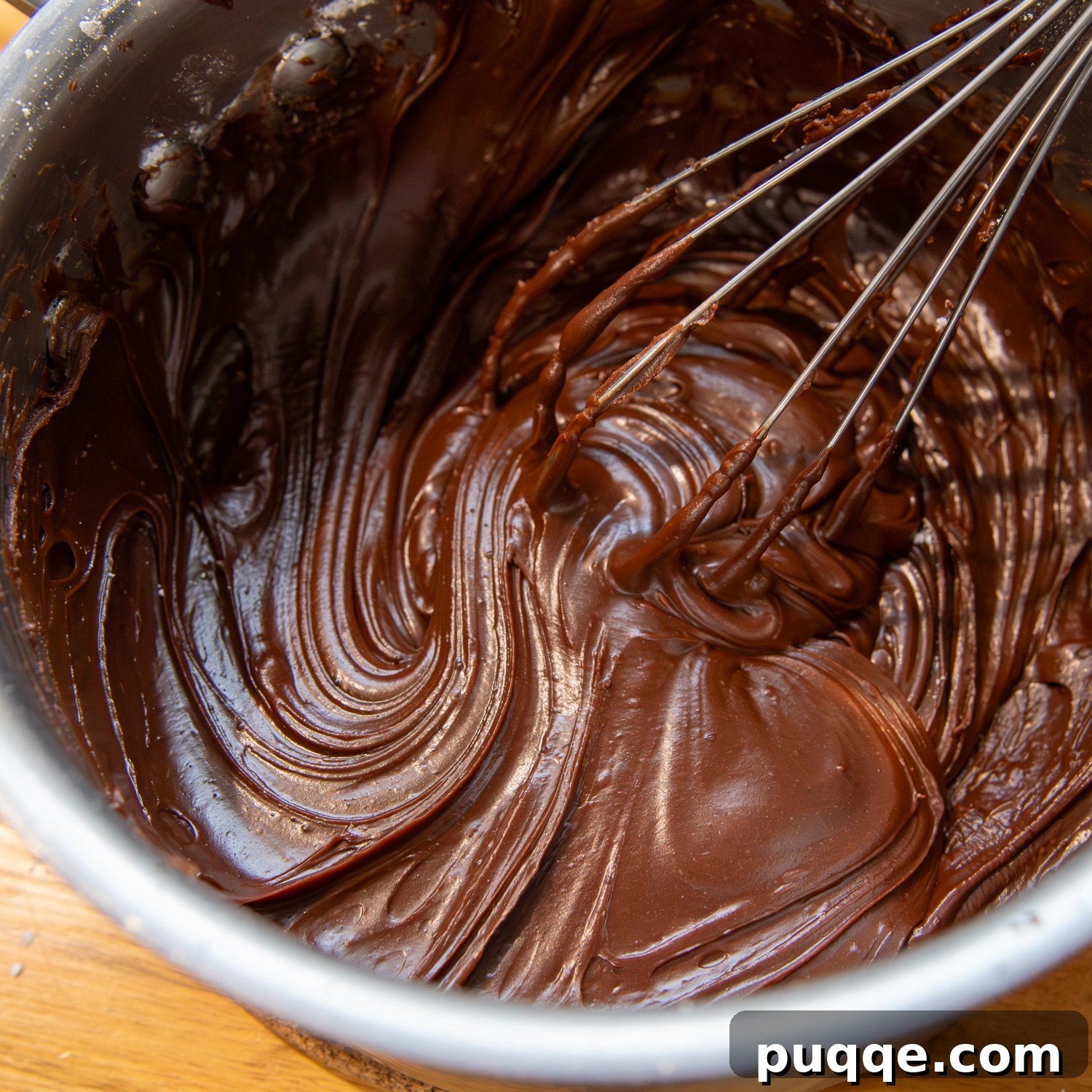 Ingredients being whisked thoroughly in a bowl to create a smooth, consistent frosting texture.