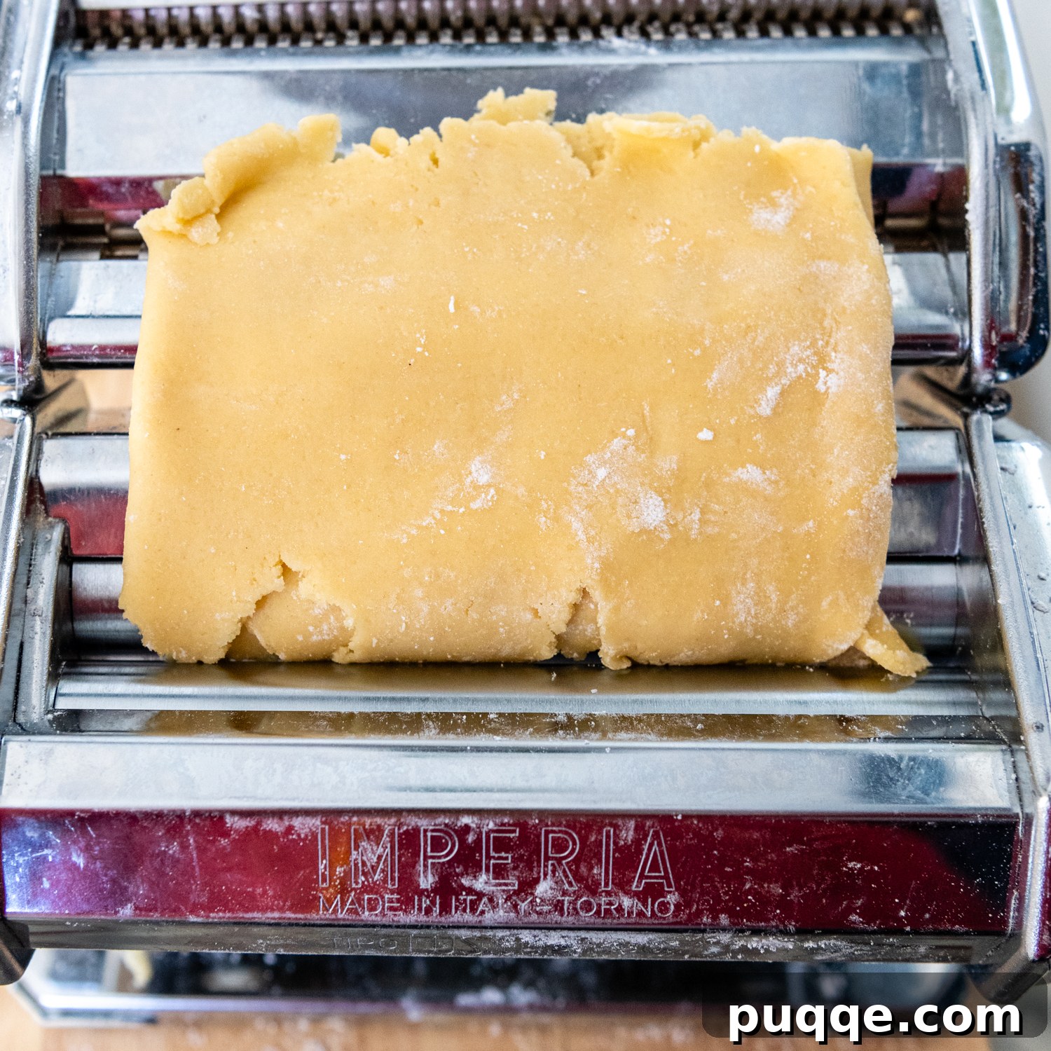 Folded dough being placed in pasta machine for second pass.