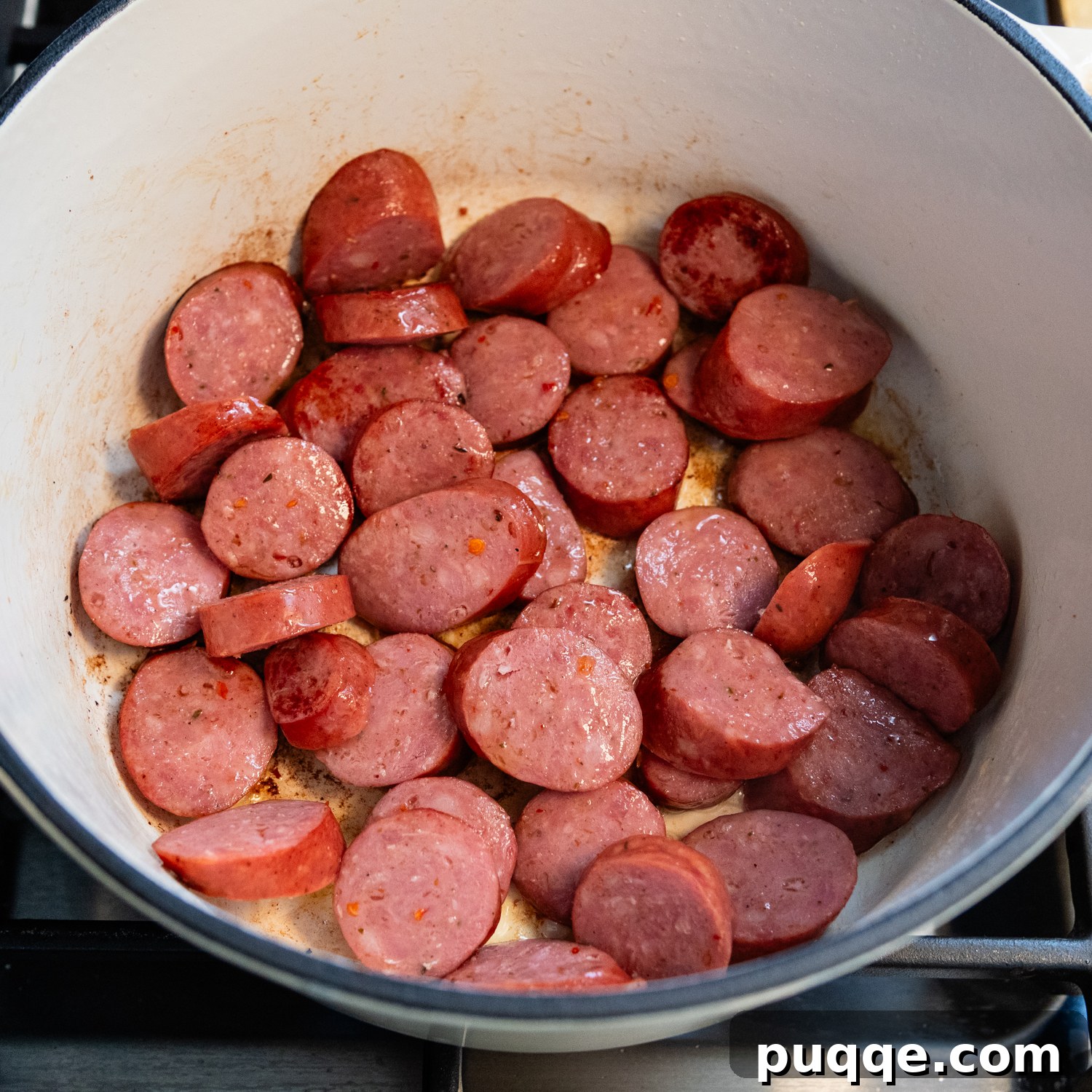 Tam Tadında Glutensiz Tek Tencere Jambalaya 3 Sliced andouille sausage browning in a large Dutch oven for gluten-free jambalaya.