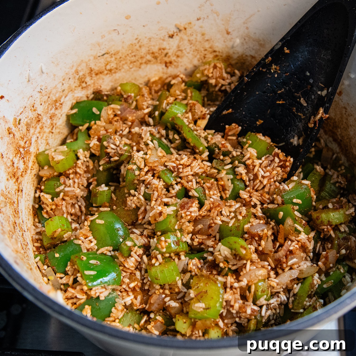 Tam Tadında Glutensiz Tek Tencere Jambalaya 7 Rinsed white rice and spices being stirred into sautéed vegetables for jambalaya.