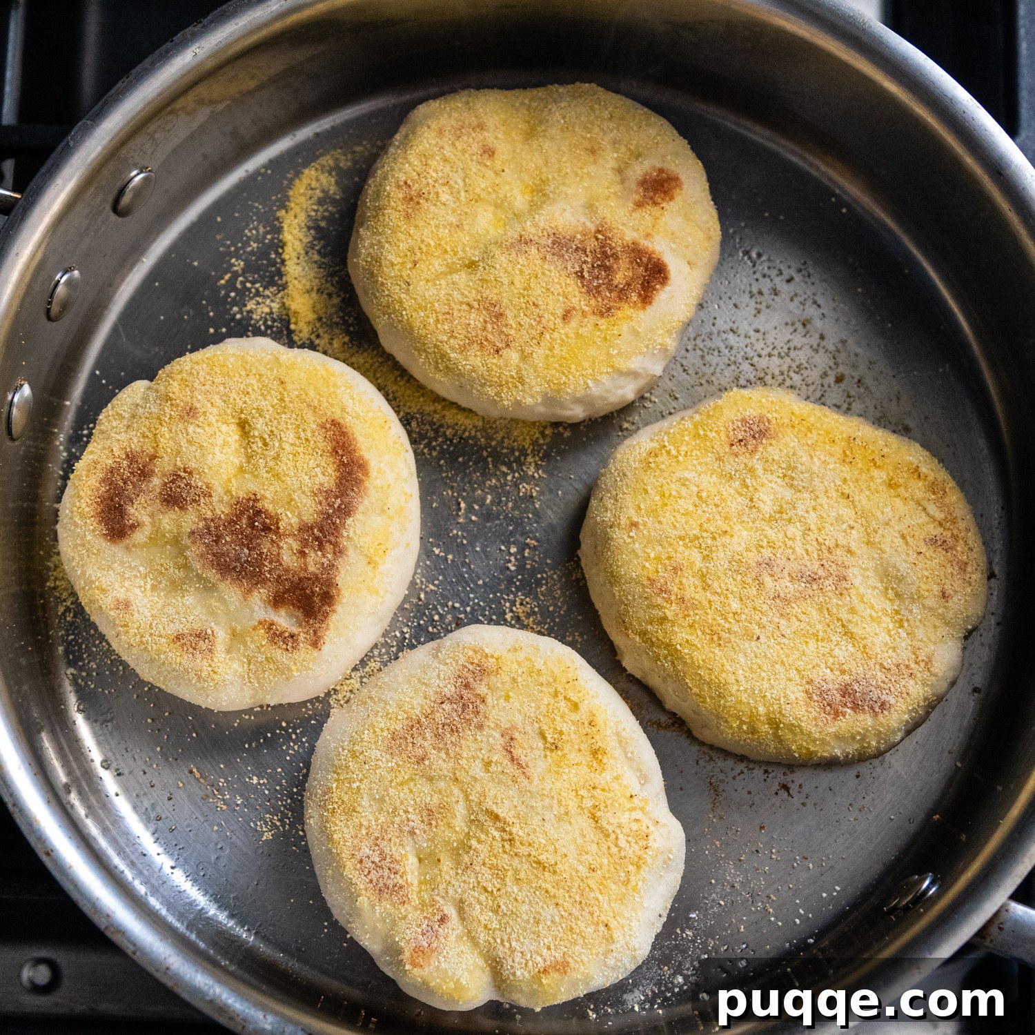 Overhead shot of browned muffins frying in a pan.