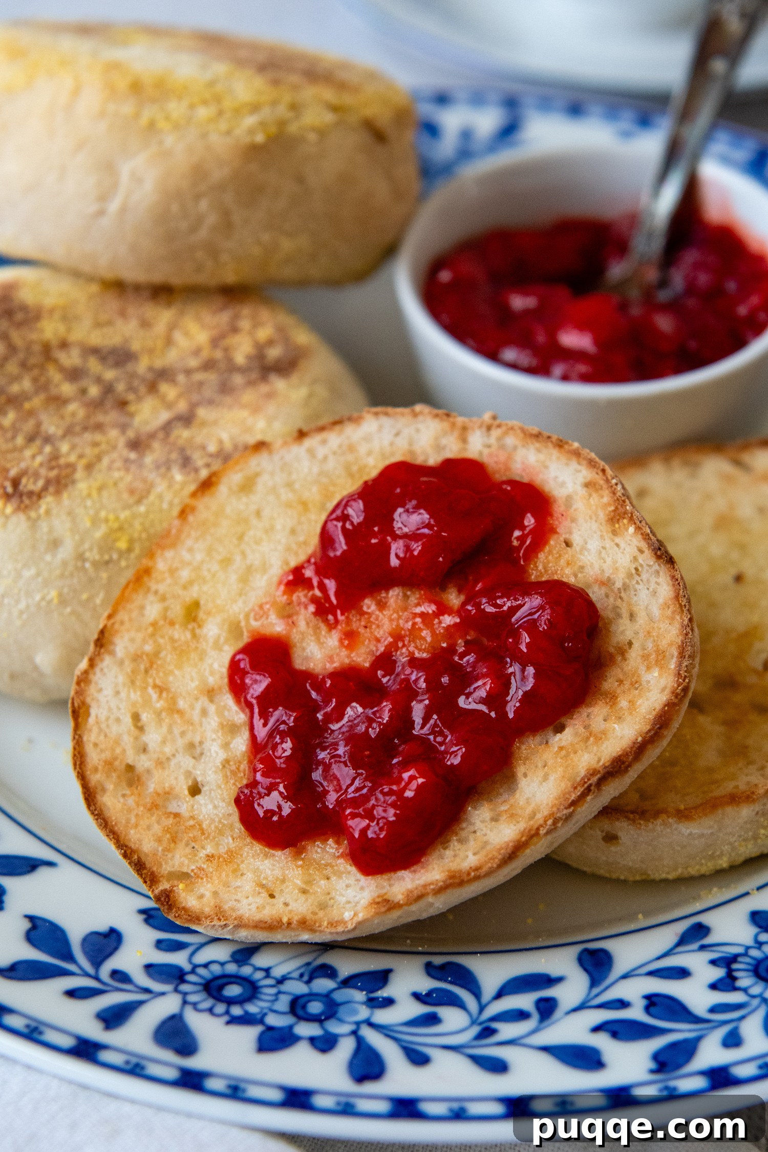 Close up of sliced open english muffin topped with preserves.
