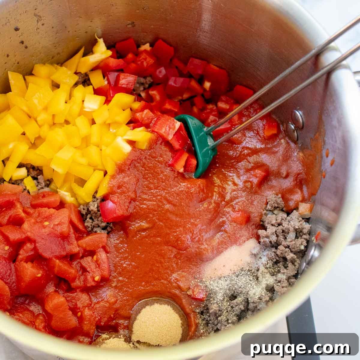 The Perfect Stuffed Pepper Soup 3 A close-up of bell peppers, diced tomatoes, and seasonings being added to the browned ground beef and onions in a large pot.