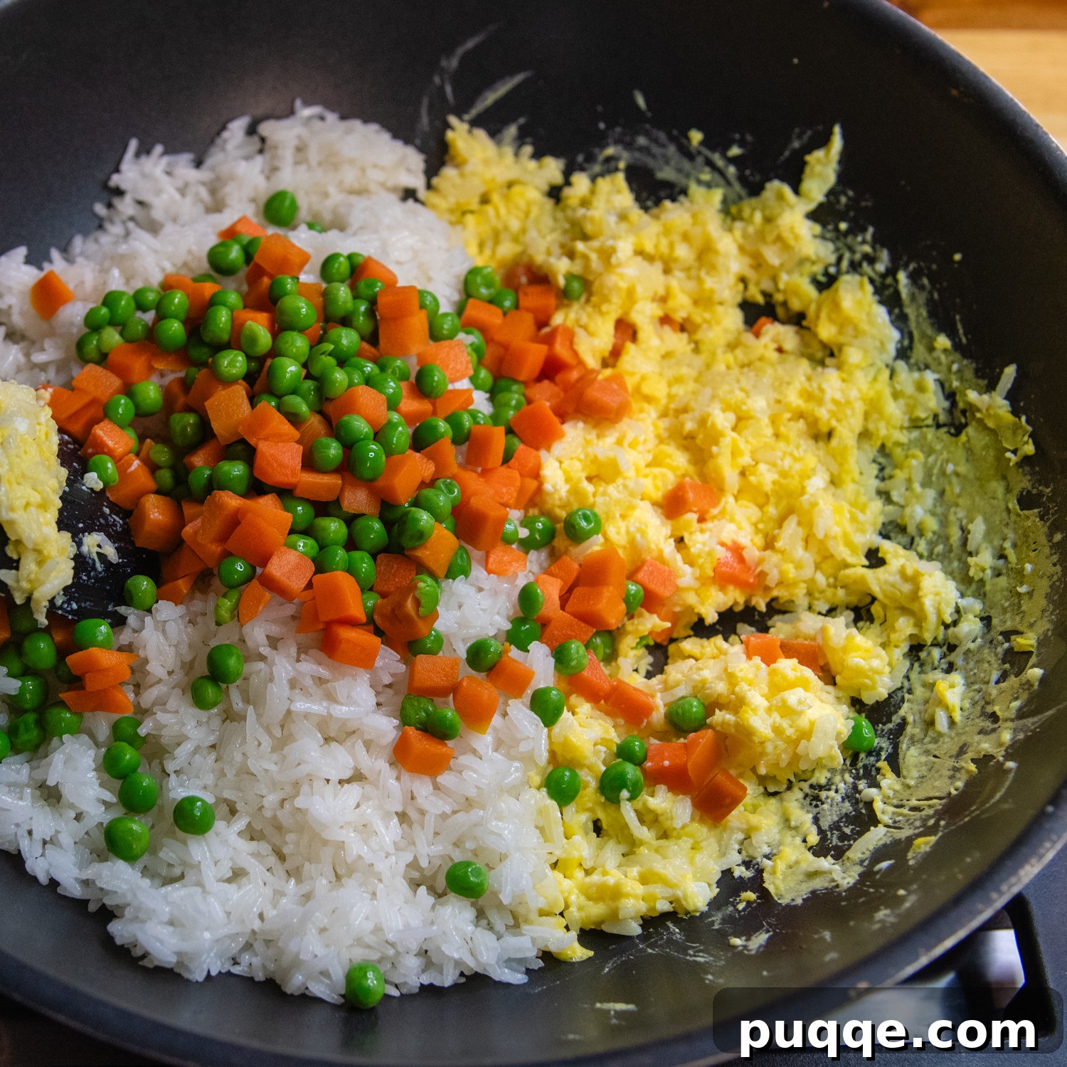 Quick Gluten-Free Fried Rice: Your Perfect Weeknight Meal 6 The final stage of gluten-free fried rice cooking in a wok, with peas, carrots, green onions, and soy sauce mixed in.