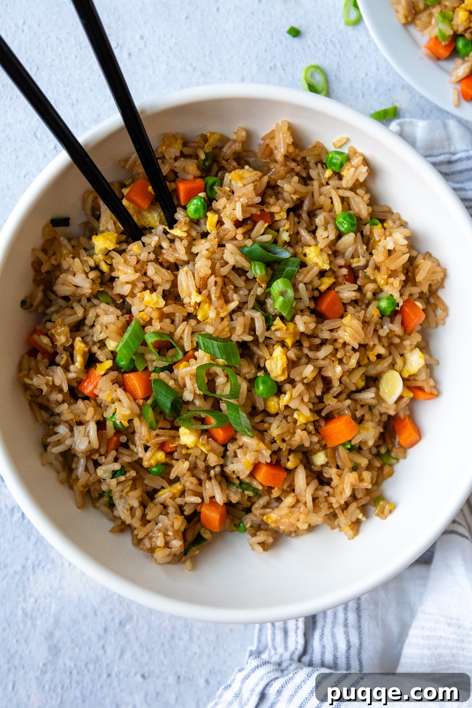 Quick Gluten-Free Fried Rice: Your Perfect Weeknight Meal 7 A close-up overhead shot of steaming gluten-free fried rice in a white bowl, with chopsticks resting on the side.
