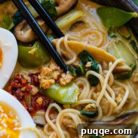 Chopsticks in a bowl with gluten-free ramen and assorted toppings.