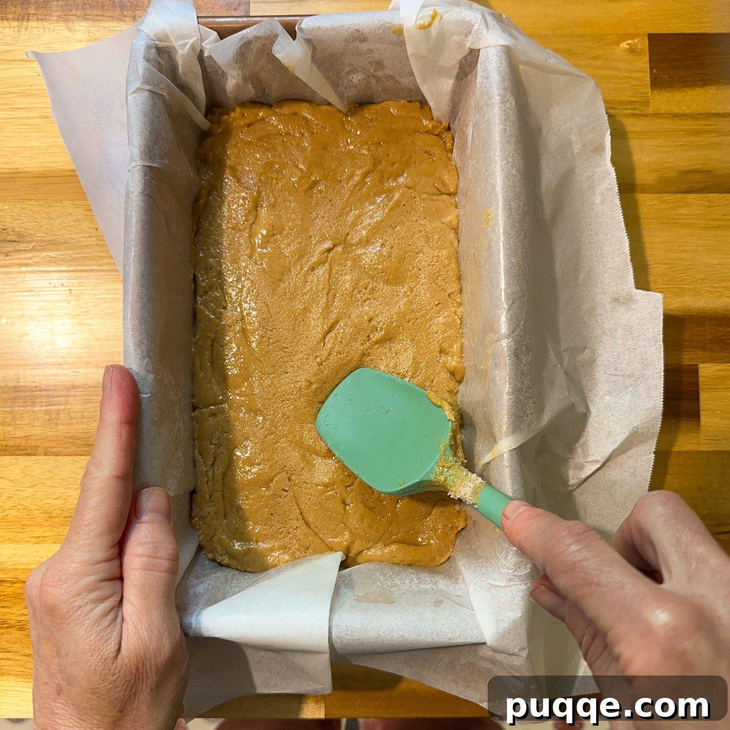 Bar mixture precisely placed and smoothed in a loaf pan with a spatula, ready for chilling.