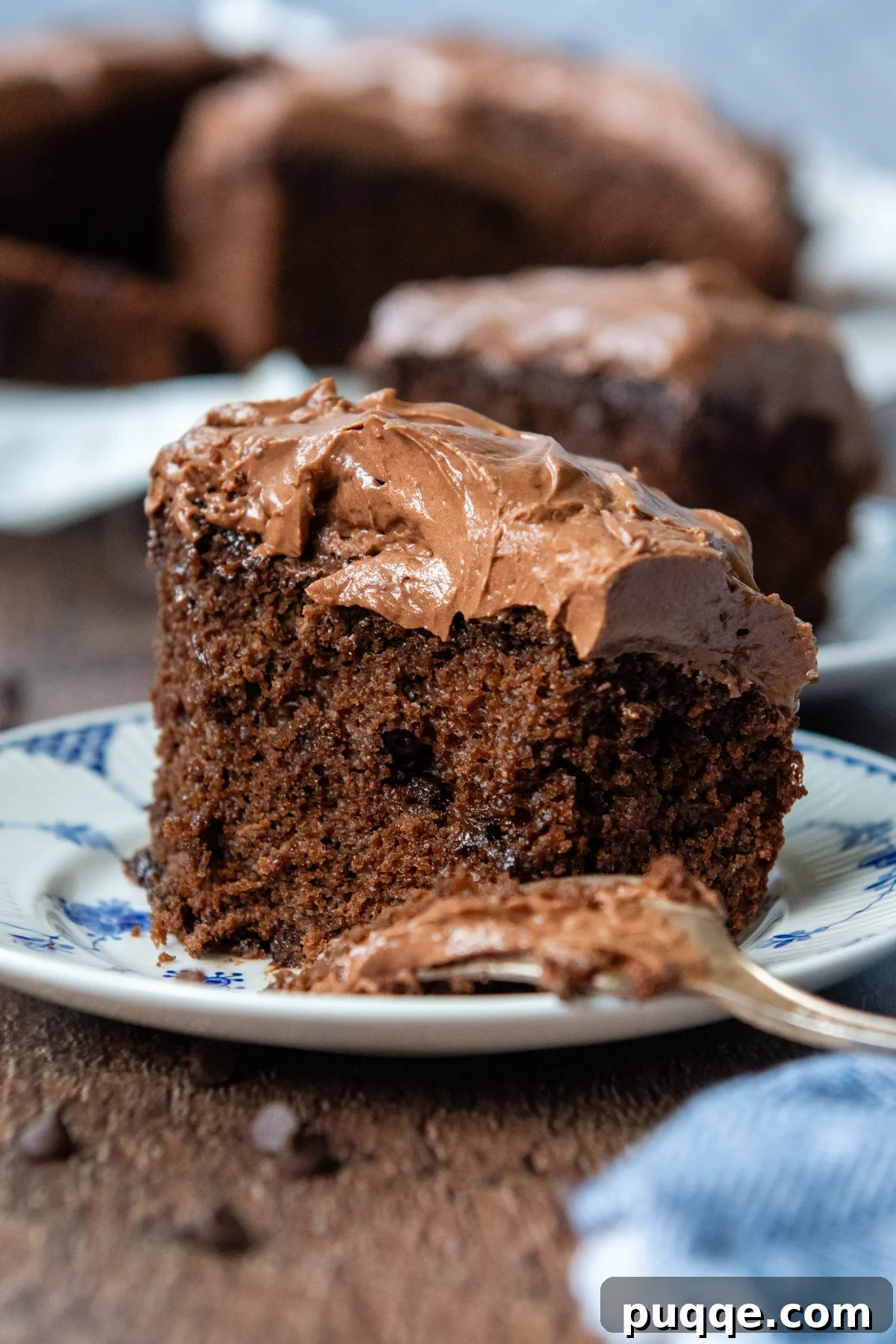 A slice of moist and fluffy oat flour chocolate cake on a plate, with a fork ready to take a bite.