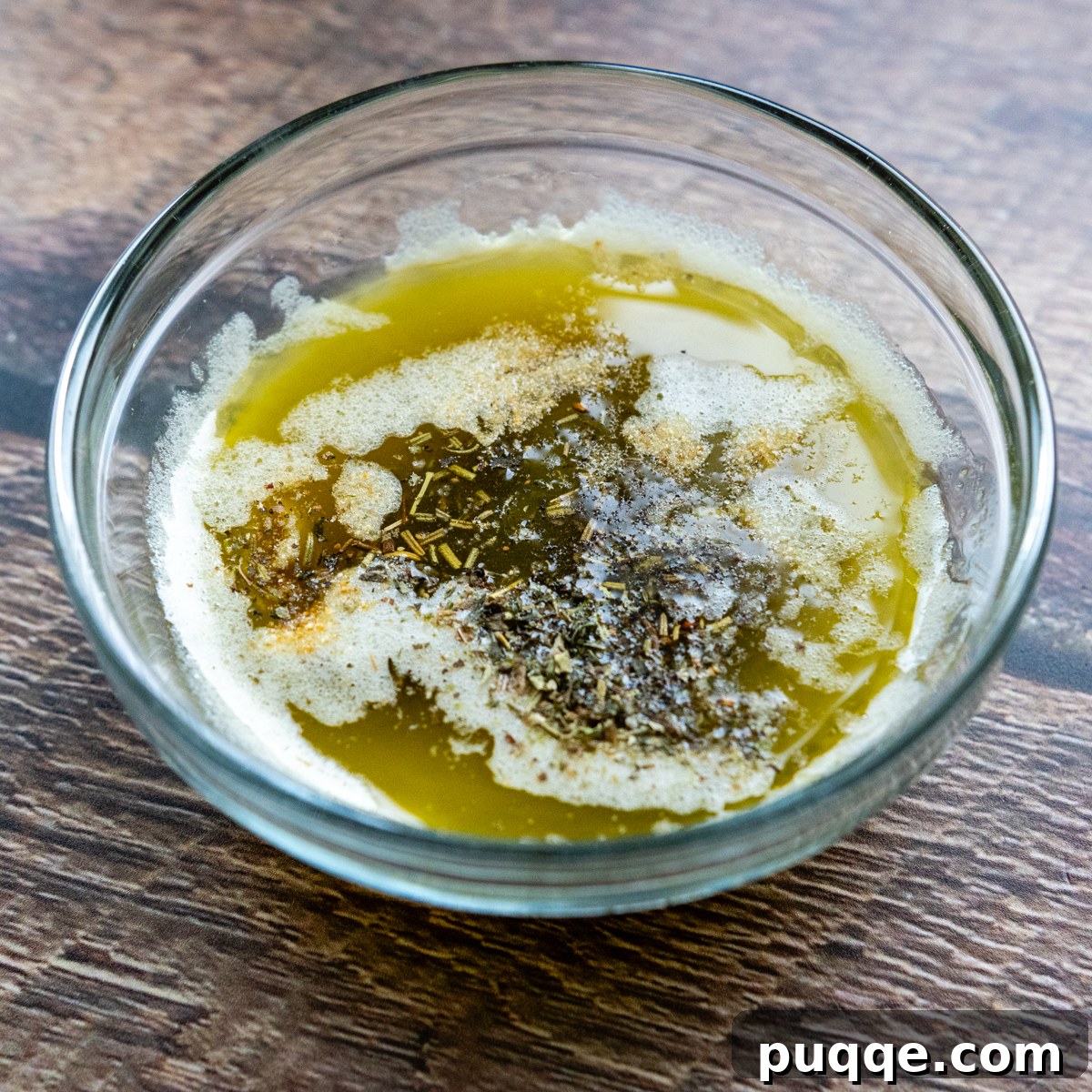 Melted butter, olive oil, and a blend of zesty seasonings in a glass bowl, ready to coat the bread.
