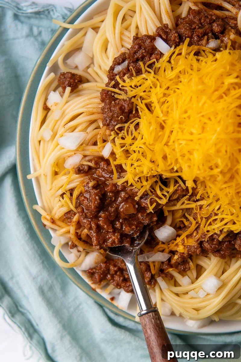 Ultimate Cincinnati Chili 2 Overhead shot of authentic Cincinnati Chili served over spaghetti with a fork, ready to eat.