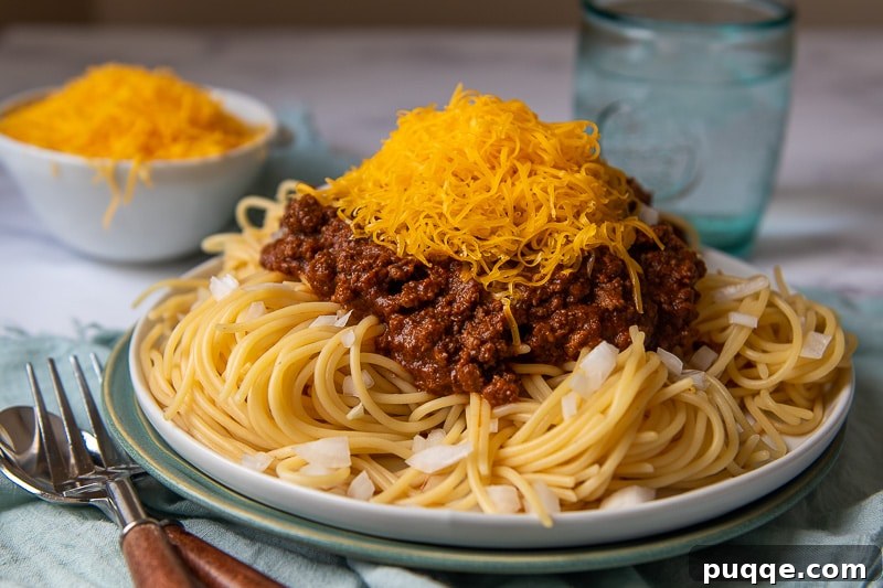 Ultimate Cincinnati Chili 7 A vibrant plate of Skyline-style Cincinnati Chili on spaghetti with a generous topping of shredded cheddar cheese.