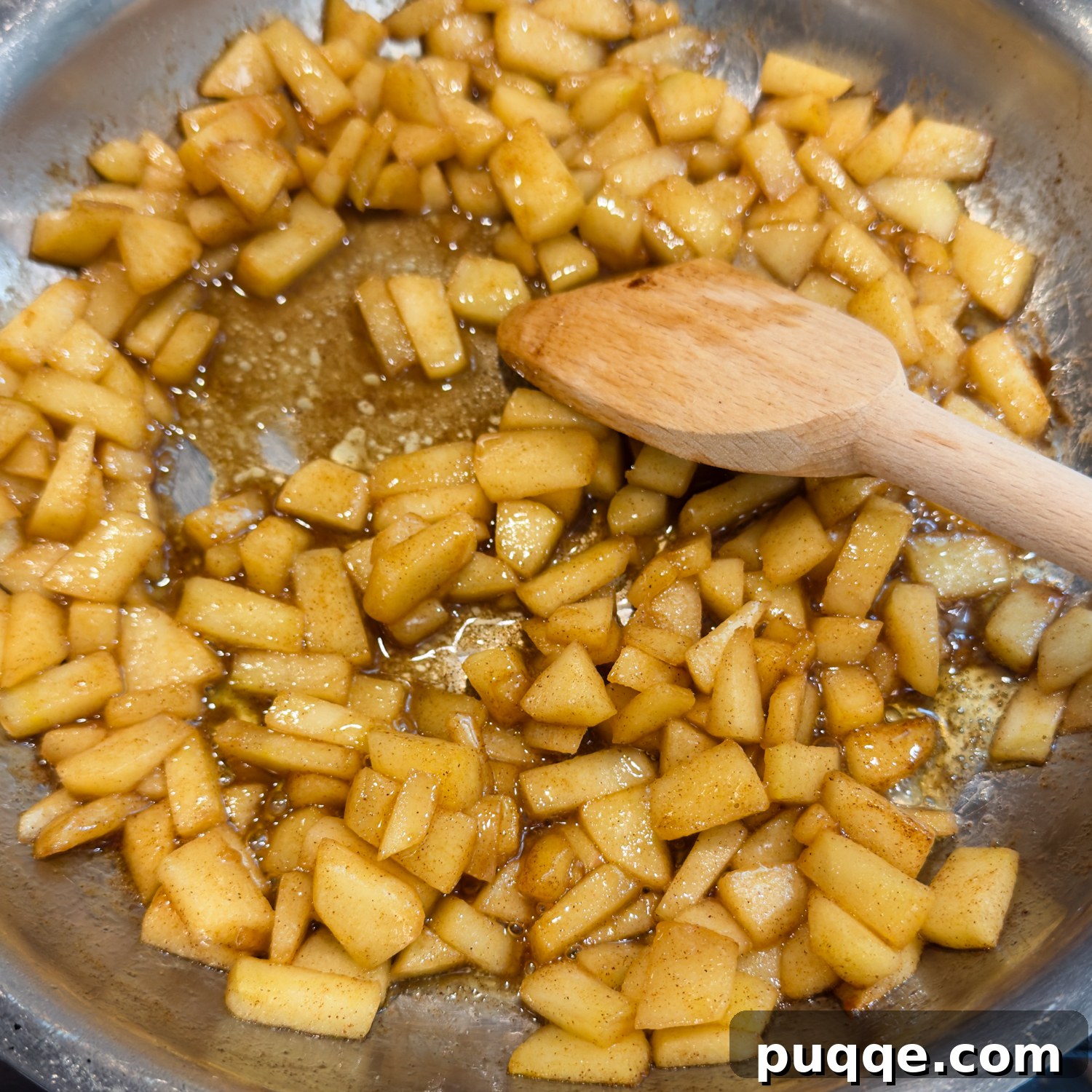 No-Fuss Gluten-Free Apple Fritters 3 Seasoned apple pieces in a bowl with wooden spoon stirring.