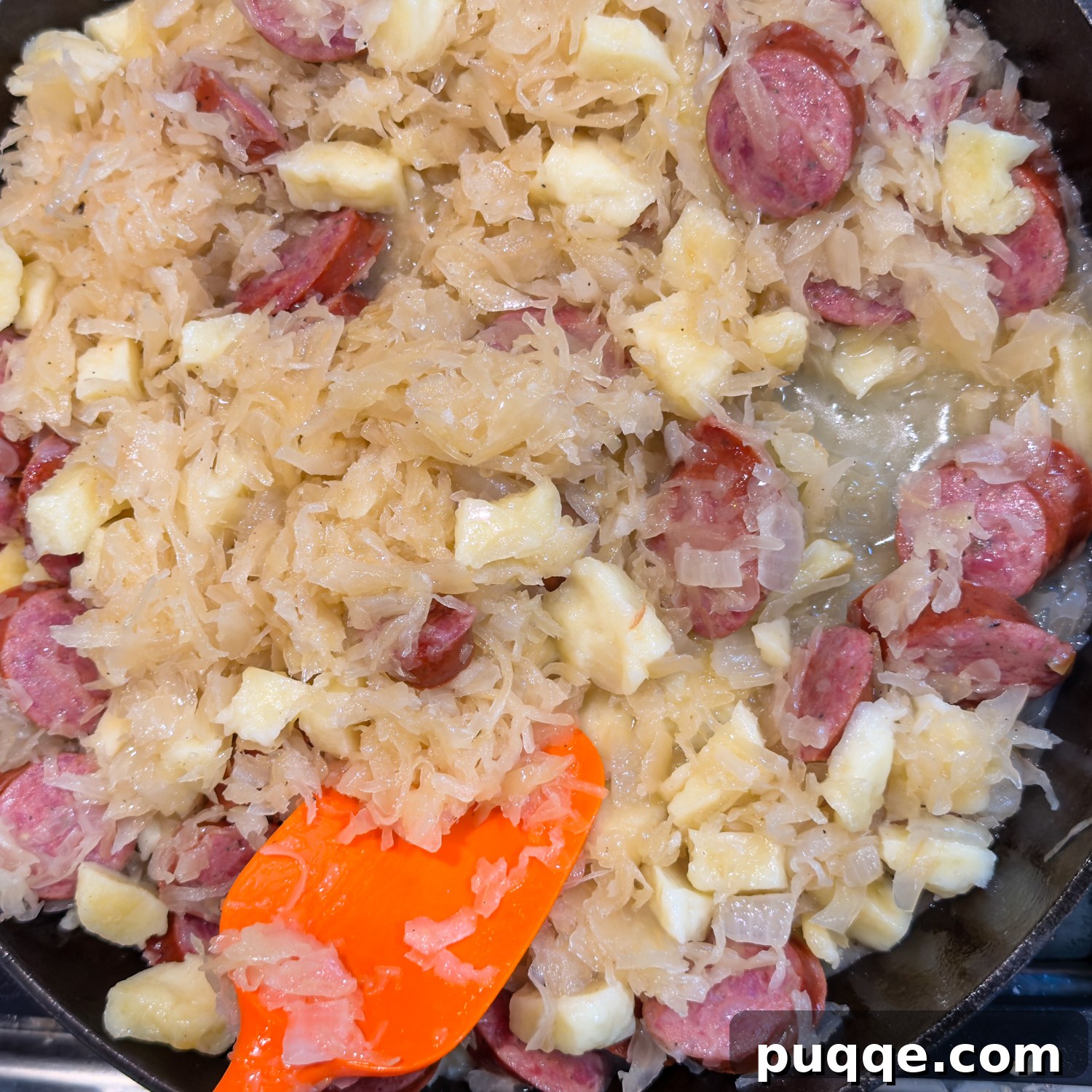 Hearty Gluten-Free German Dumplings and Sausage 8 A cast iron skillet filled with simmering sauerkraut, sausage, onions, and gluten-free dumplings, completing the dish.