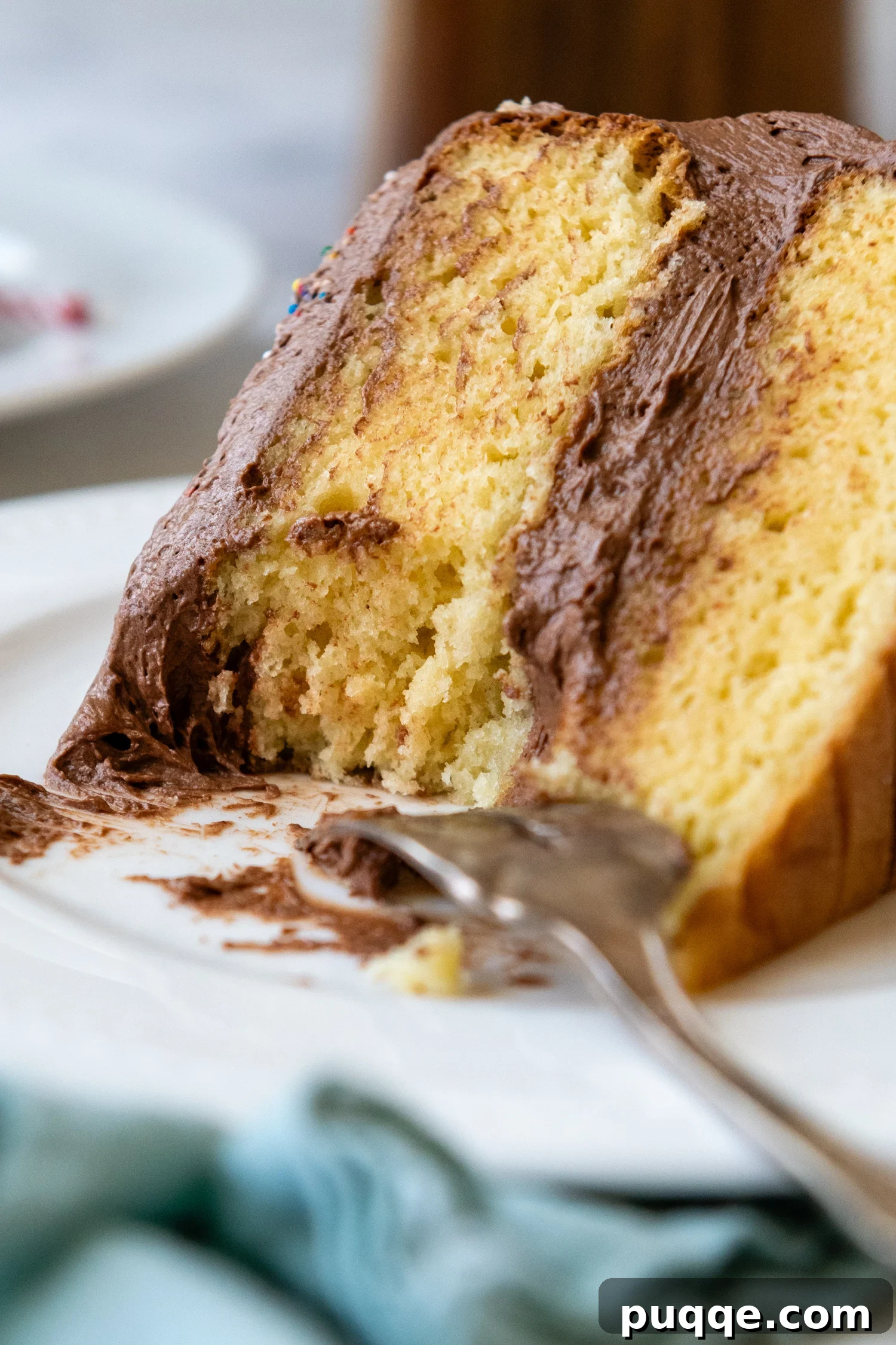 Gluten-Free yellow cake slice laying on it's side on a white plate with a fork.