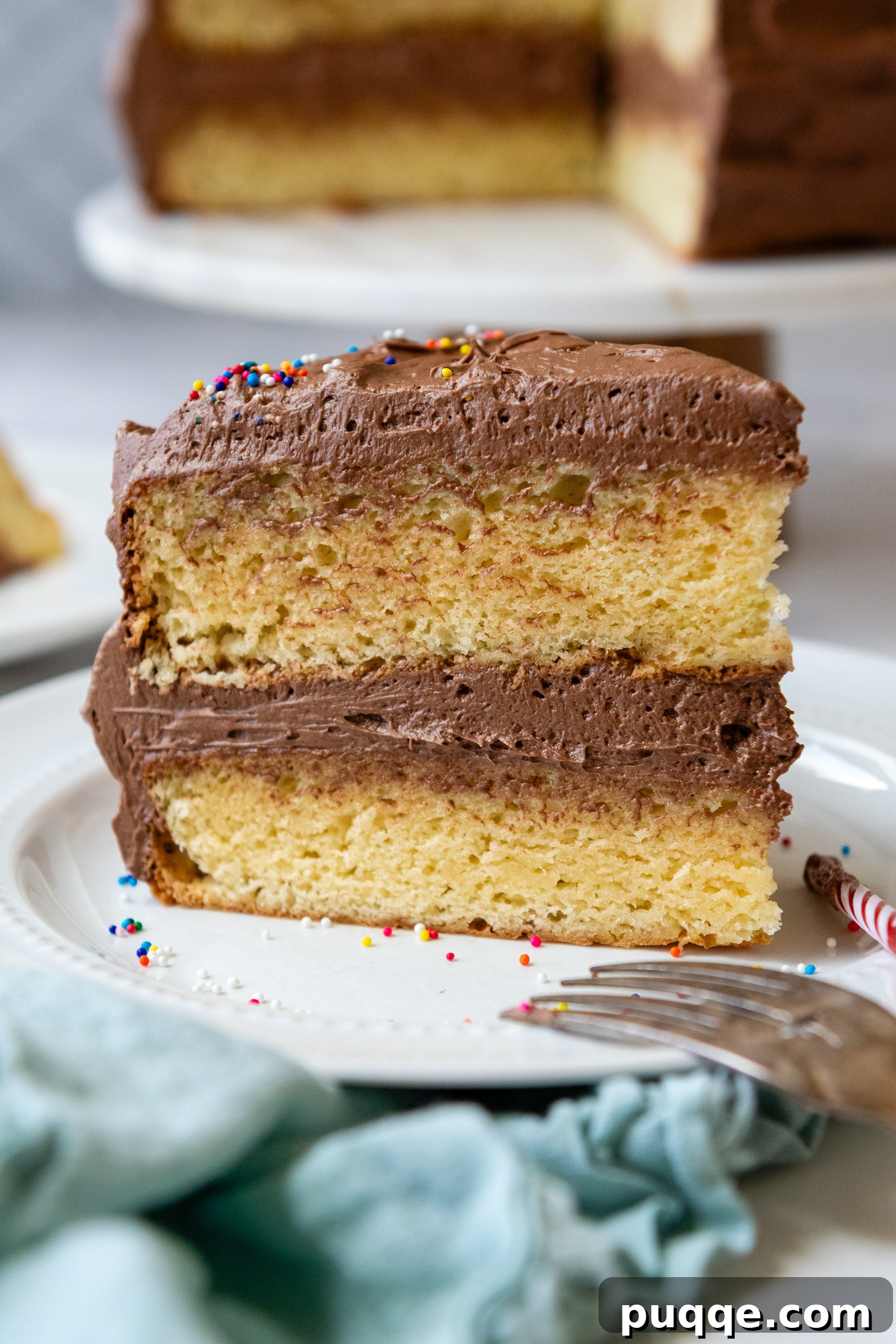 Slice of cake on showing two layers of frosting on a white plate.